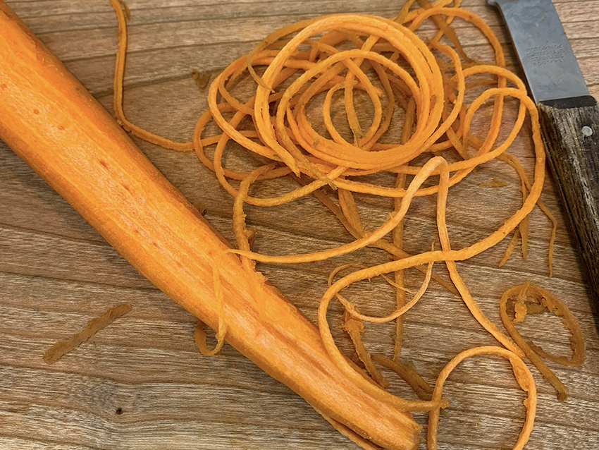 Pressing firmly, glide the zester down the carrot from top to bottom.