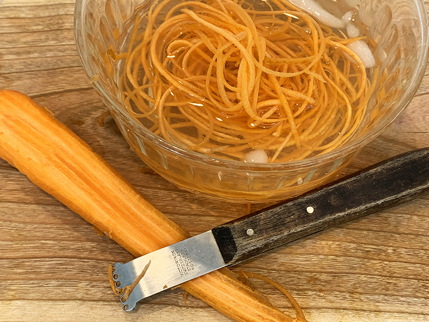 As you work, put the carrot threads in a bowl of ice water.